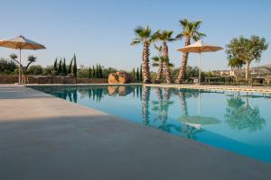 a swimming pool with palm trees and umbrellas at Resort Fontes Episcopi in Aragona