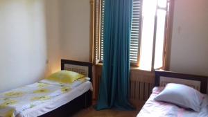 um quarto com 2 camas e uma janela com cortinas azuis em Guest House Metreveli Street 19 em Khashuri