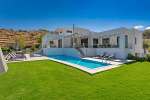 a villa with a swimming pool and a yard at Eolia Iconic Villa, walking distance to the beach, By ThinkVilla in Panormos Rethymno