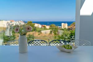 a table with a vase of flowers and a bowl of fruit at Eolia Iconic Villa, walking distance to the beach, By ThinkVilla in Panormos Rethymno