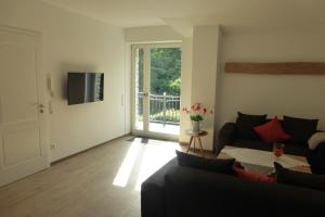 a living room with a couch and a sliding glass door at Ferienwohnung am Eifelsteig in Roetgen