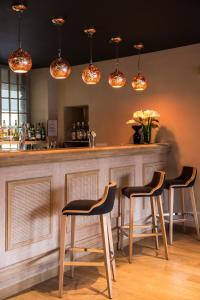 a bar with three stools at a counter with lights at Hotel de l'Abbaye; BW Premier Collection in Le Tronchet