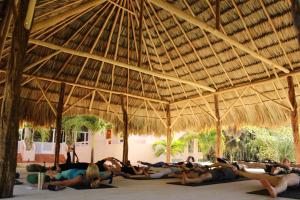 a group of people laying on the floor under a straw roof at The Crimson Orchid Inn at Orchid Bay in San Fernando