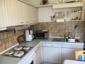 uma pequena cozinha com armários brancos e um lavatório em VormHolte em Radevormwald