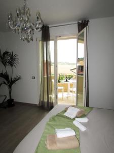 a bedroom with a bed with green sheets and a chandelier at B&B Bellavista in Tavullia