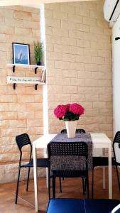 a table with chairs and a vase of flowers on it at Mini Loft Porto Torres in Porto Torres