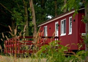 a red cabin in the woods with trees at Erlebnishof Katthusen in Otterndorf