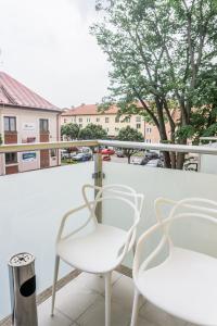 2 sillas blancas sentadas en un balcón en Premium Apartment Centrum, en Poprad