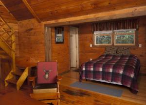 1 dormitorio en una cabaña de madera con 1 cama y 1 silla en Cobblescote on the Lake en Cooperstown