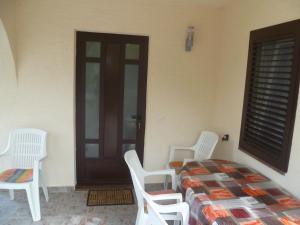 a room with white chairs and a bed and a door at Vesna Pag Potočnica in Borovići +4 photos