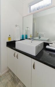 a white bathroom with a sink and a mirror at Palm Court Motor Inn in Rotorua