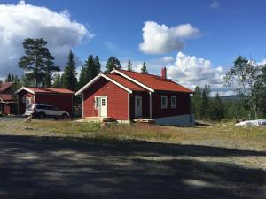 a red house with a car parked in front of it at Fjällhus 1 in Höstsätern