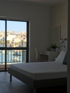 ein Schlafzimmer mit einem Bett und einem großen Fenster in der Unterkunft Sunrise Creek in Marsaskala