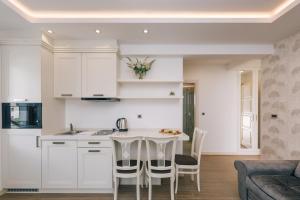a kitchen with white cabinets and a table and chairs at Splendido MB Apartments in Tivat