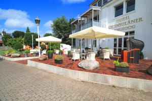 a patio with tables and umbrellas in front of a building at Hotel De Insulåner in Langeoog