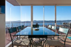 a glass table on a balcony with a view of the water at 567 Sandy Bay in Hobart