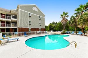 a swimming pool in front of a building with palm trees at Siegel Select Gautier in Gautier