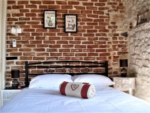 a bed with two pillows in front of a brick wall at Elisw in Afitos