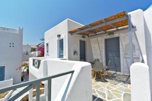 a white house with a patio and a fence at Teoria Paros - Matsas Windmill in Naousa