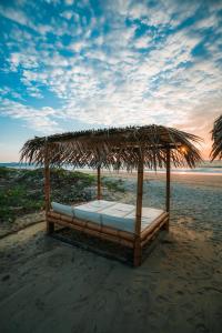 ein Bett unter einem Strohschirm am Strand in der Unterkunft Makani Vichayito in Vichayito