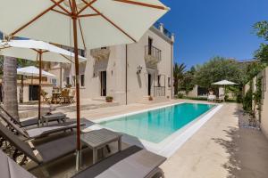 a swimming pool with two chairs and an umbrella at Villa Raphael in Avola