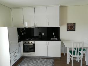a white kitchen with a table and white cabinets at Quinta da Portelada in Peso da Régua