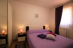 a bedroom with a purple bed with two lamps at Apartments Supra Mare in Rabac