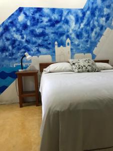 a bedroom with a white bed and a blue sky at Casa De La Luz - Guesthouse in Tlacotalpan