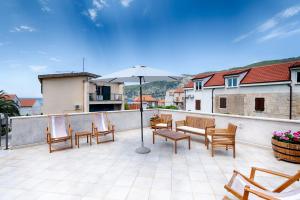 eine Terrasse mit einem Tisch, Stühlen und einem Sonnenschirm in der Unterkunft Apartments Kastelani in Komiža