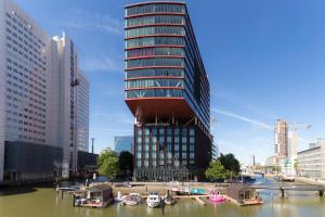 a tall building next to a river with boats in it at Wikkelboats at Wijnhaven in Rotterdam