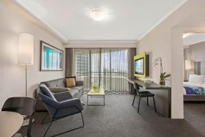 a living room with a couch and a desk and a bed at Mantra Parramatta in Sydney