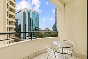 balcón con mesa, sillas y vistas a la ciudad en Mantra Parramatta en Sídney