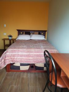 Machachi的住宿－Casa del Montañero，一张床位,位于带书桌和床的西德西德西德(Sidx sidx)客房内