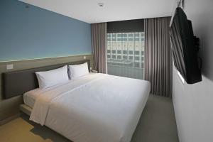 una camera con letto bianco e TV a schermo piatto di Amaris Hotel Fachrudin – Tanah Abang a Giacarta
