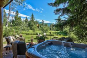 a hot tub on a patio with a view of a yard at A Suite Retreat - Beyond Bed & Breakfast in Sun Peaks
