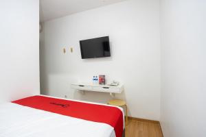 RedDoorz Plus @ Danau Sunter Utara في جاكرتا: غرفة نوم مع سرير وتلفزيون على الحائط