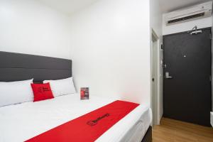 RedDoorz Plus @ Danau Sunter Utara في جاكرتا: غرفة نوم مع سرير مع بطانية حمراء عليه