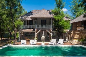 a house with a swimming pool and lounge chairs at Coral Flora Villa Beach Front in Gili Trawangan