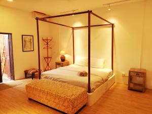a bedroom with a four post canopy bed and a stool at Coco Country Homes in Melaka