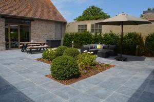 un patio con sombrilla, sofá y mesa en Vakantiewoning Den Landman, en Nieuwpoort