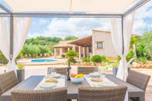 een patio met een tafel en stoelen en een zwembad bij Son Pere Genet in Búger