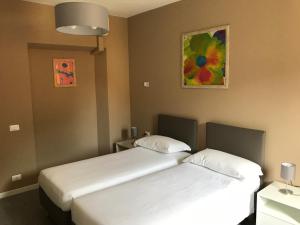 two beds in a hotel room with a painting on the wall at Casa Patrizia in Gravellona Toce