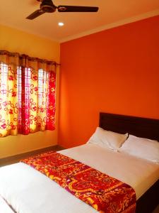 a bedroom with two beds with orange walls and curtains at Rexon Residency in Kattappana