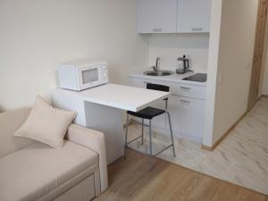 a white kitchen with a couch and a table with a microwave at SMART-HOUSE Smart-kvartira s kukhnei. in Kyiv