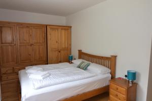 バードガシュタインにあるApartment Steinbockの白いベッドと木製キャビネット付きのベッドルーム1室が備わります。