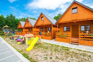 a wooden house with a playground with a slide at Domki KARO in Rowy