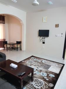 uma sala de estar com uma mesa e uma televisão na parede em Today House Suites em Salalah