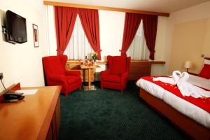 a hotel room with a bed and two red chairs at Hotel Slovan in Jeseník