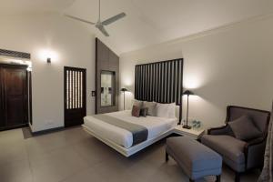 Andores Resort And Spa - Calangute في كالانغيُت: غرفة نوم بسرير واريكة وكرسي