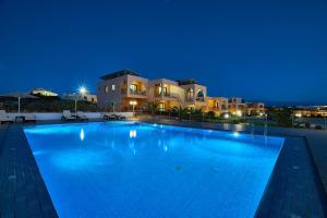 a large swimming pool in front of a house at night at Nanakis Beach Apartments in Stavros